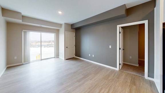 A spacious room with wooden flooring and a large window.