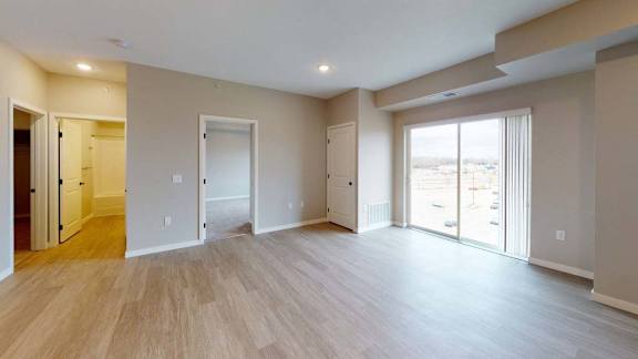 A spacious room with wooden floors and sliding glass doors.