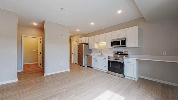 A kitchen with white cabinets and a wooden floor.