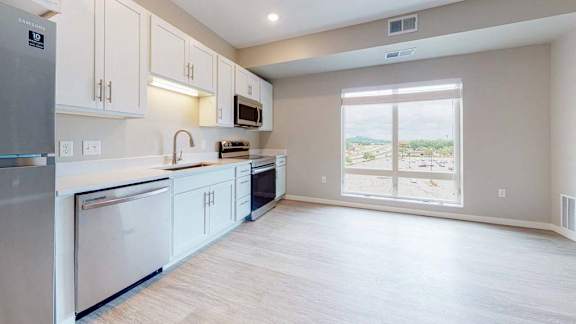A kitchen with white cabinets and a large window overlooking a desert landscape.