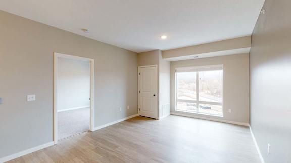 A spacious room with a door on the left and a window on the right.