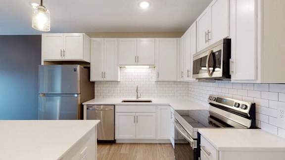 A modern kitchen with white cabinets and stainless steel appliances.