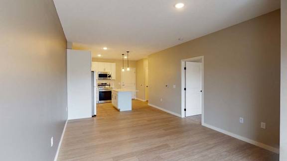 A spacious room with a kitchen area in the background.