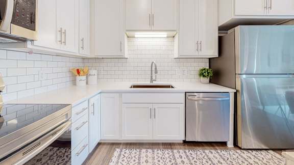 A kitchen with white cabinets and a stainless steel refrigerator.