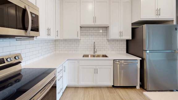 A modern kitchen with white cabinets and stainless steel appliances.