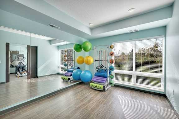 A room with a mirror, exercise equipment, and a window with blinds.