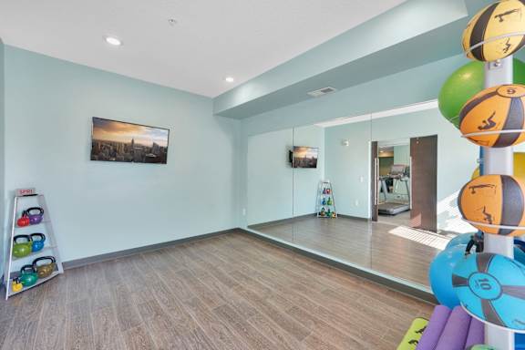 A room with a wooden floor and a large mirror on the wall.