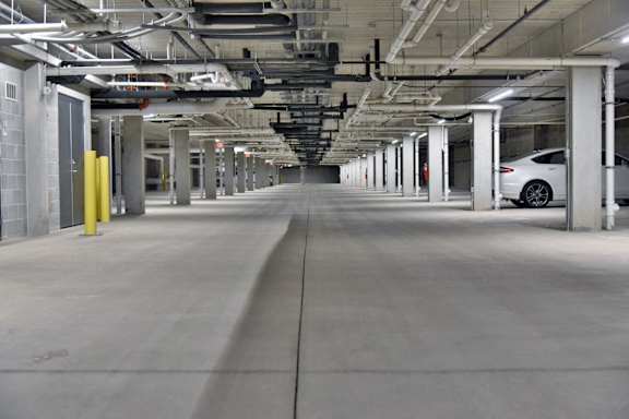 A long, empty parking garage with a white car parked on the right side.