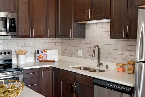 A kitchen with brown cabinets and a white counter.