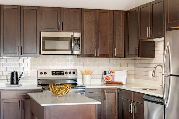 A kitchen with dark brown cabinets and a stainless steel refrigerator.