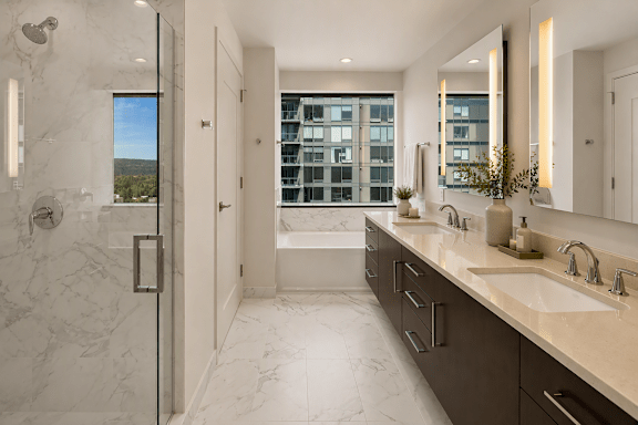 A bathroom with a marble floor and walls, a large mirror, and a window with a view of a cityscape.
