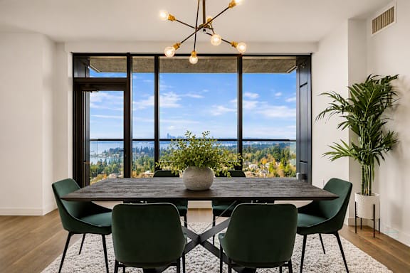 A dining room with a table and chairs and a view of the outdoors.