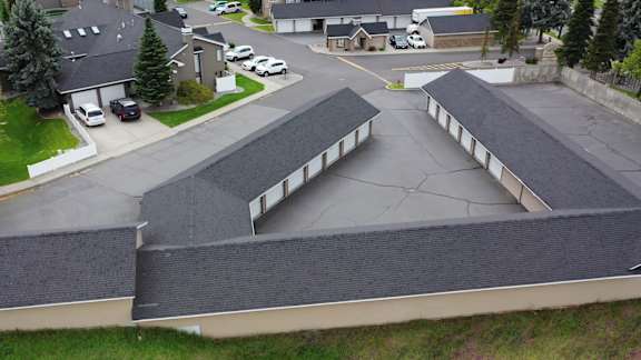 A parking lot with a few cars and a building with a grey roof at Graymayre Crossing Apartments, Spokane, 99208