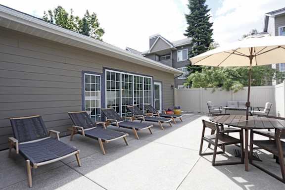 A patio with a table, chairs and an umbrella at Graymayre Crossing Apartments, Spokane, WA, 99208