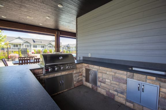 an outdoor kitchen with a barbecue and a patio at The Brix Apartments, Spokane Valley, WA, 99037