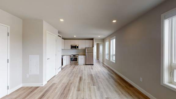 A long, empty hallway with wooden floors and white walls.