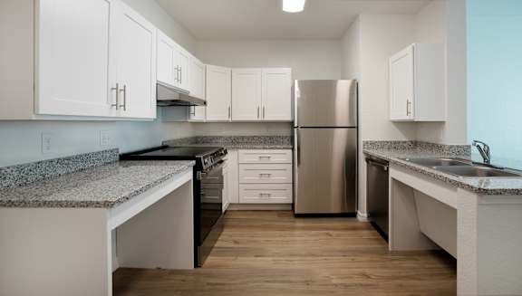 A kitchen with a refrigerator, sink, and cabinets.