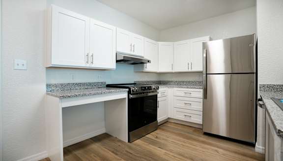 A kitchen with a stainless steel refrigerator and a granite countertop.