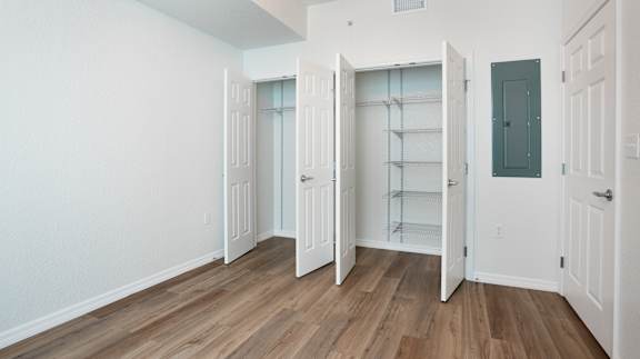 A room with white walls and wooden flooring with four doors.
