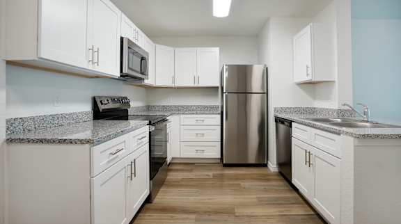 A kitchen with white cabinets and a stainless steel refrigerator.