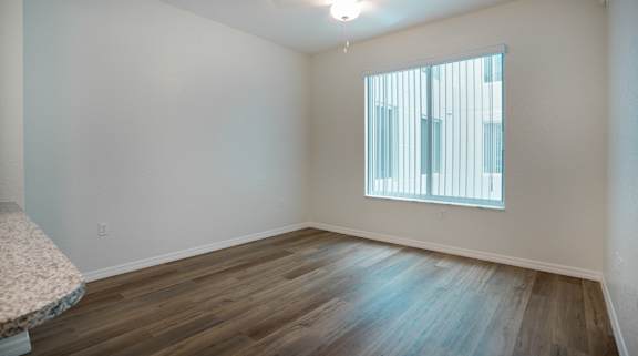 A room with wooden flooring and a window with blinds.