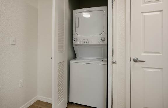 A white dishwasher is in a narrow hallway.