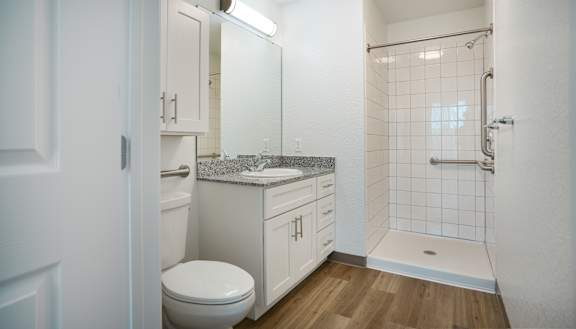 A white bathroom with a toilet, sink, and shower.