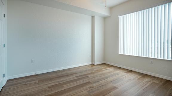 A room with wooden flooring and a window with blinds.