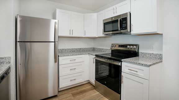 A kitchen with a stainless steel refrigerator, microwave, oven, and cabinets.