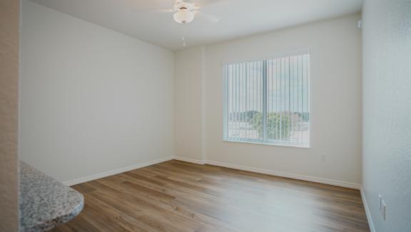 Empty room with a window and wooden floor.