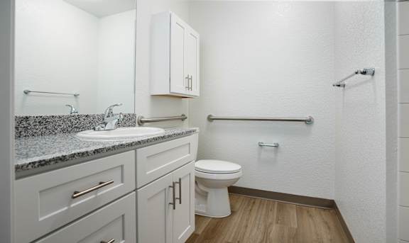 A white bathroom with a sink, toilet, and shower.