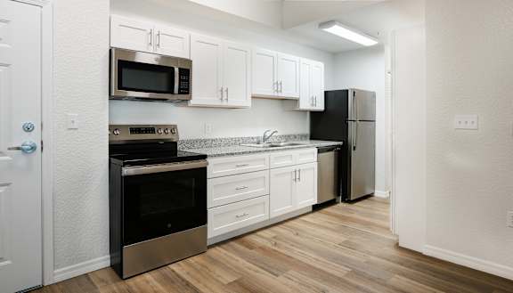 A kitchen with white cabinets and a black fridge.