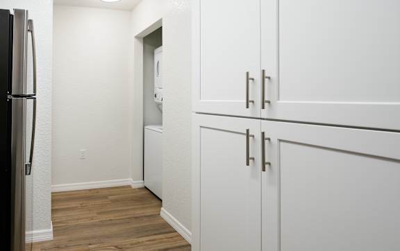 A kitchen with white cabinets and a black fridge.