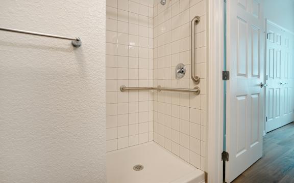 A white bathroom with a white tub and white tiles.