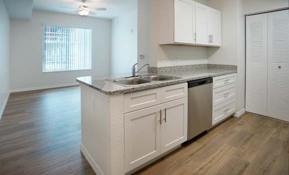 A kitchen with white cabinets and a granite countertop.
