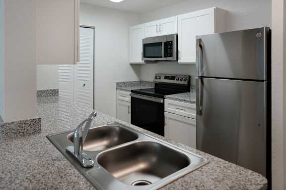 A modern kitchen with a stainless steel refrigerator, microwave, and oven.