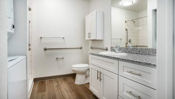 A white bathroom with a toilet, sink, and a mirror.