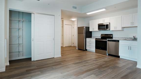 A kitchen with white cabinets and a black fridge.