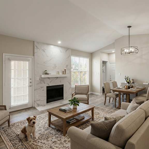 A dog sits on a rug in a living room with a fireplace and a dining area.