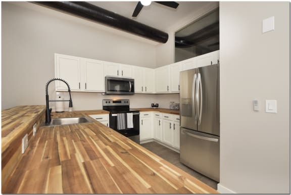 a kitchen with a wooden counter top and a stainless steel refrigerator