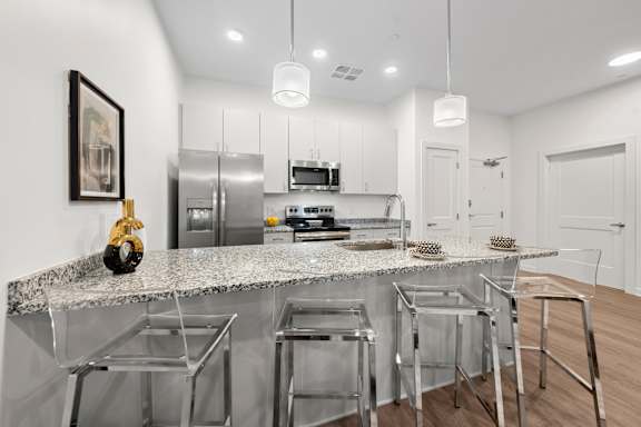 A modern kitchen with a granite countertop and stainless steel appliances. at The Lumos Apartments, Ohio