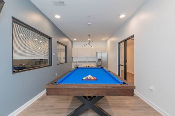 A pool table in a room with a window and a door. at The Lumos Apartments, Cleveland, OH, 44106