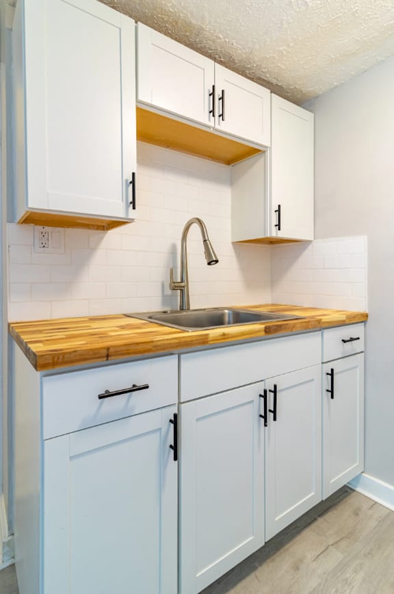A kitchen with white cabinets and a wooden countertop.