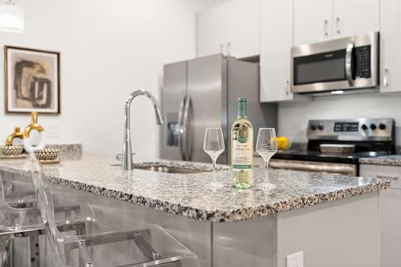 A kitchen with a granite countertop and a wine glass on it. at The Lumos Apartments, Cleveland, Ohio