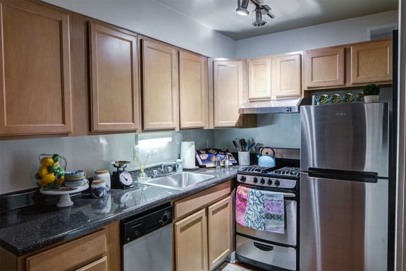 a kitchen with wooden cabinets and stainless steel appliances at Heritage Apartments, Ohio