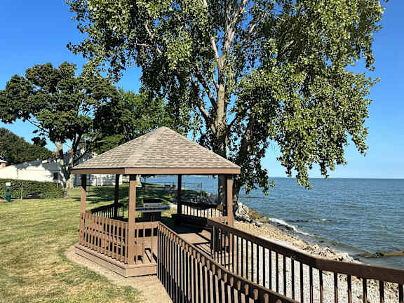 A gazebo sits on a wooden deck overlooking a body of water.