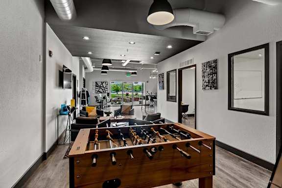 A foosball table is in the middle of a room with a lot of windows. at Vivo Toledo Apartments, Toledo, OH, 43607