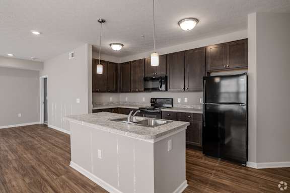 A kitchen with a black refrigerator and wooden cabinets.at The Residences at Akita Lane, Canal Winchester, 43110