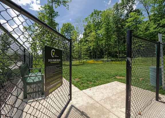the gate to the dog park is open and there is a green lawn and trees at The Bend, Lancaster, OH, 43130