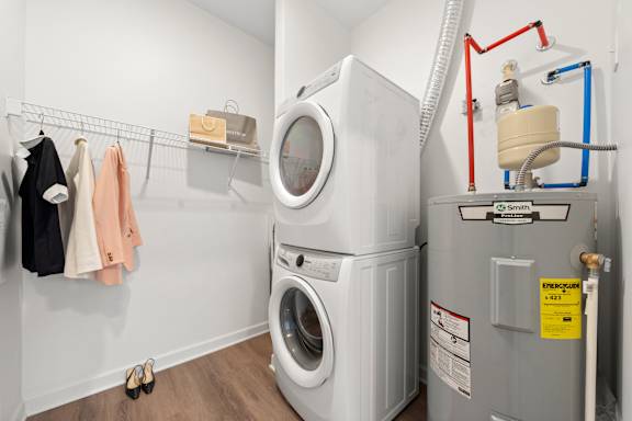 A washing machine and dryer in a small laundry room. at The Lumos Apartments, Cleveland, OH, 44106
